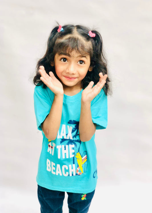 Child wearing a blue t-shirt with 'Laze at the Beaches' text and graphics on a plain background