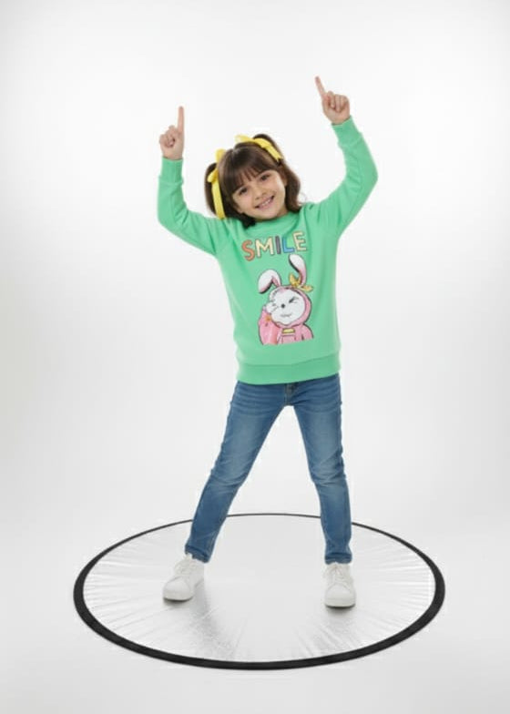 Child wearing a green sweater with cartoon characters, blue jeans, and headphones on a white background