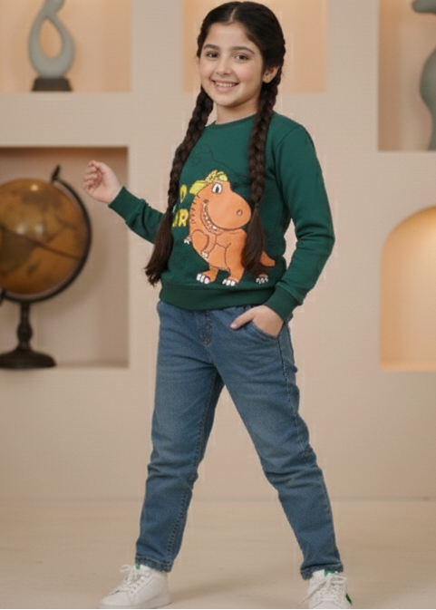 Child in a green sweater with a Dinosaurs design and blue jeans standing in a decorative room with plants and sculptures.