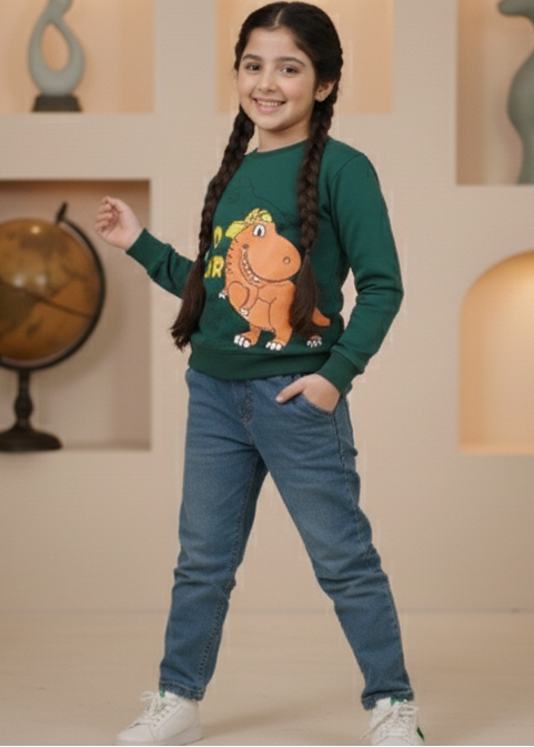 Child in a green sweater with a Dinosaurs design and blue jeans standing in a decorative room with plants and sculptures.