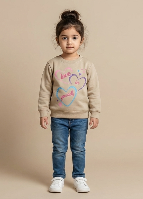 Child wearing a tan sweatshirt with a colourful heart design on a beige background