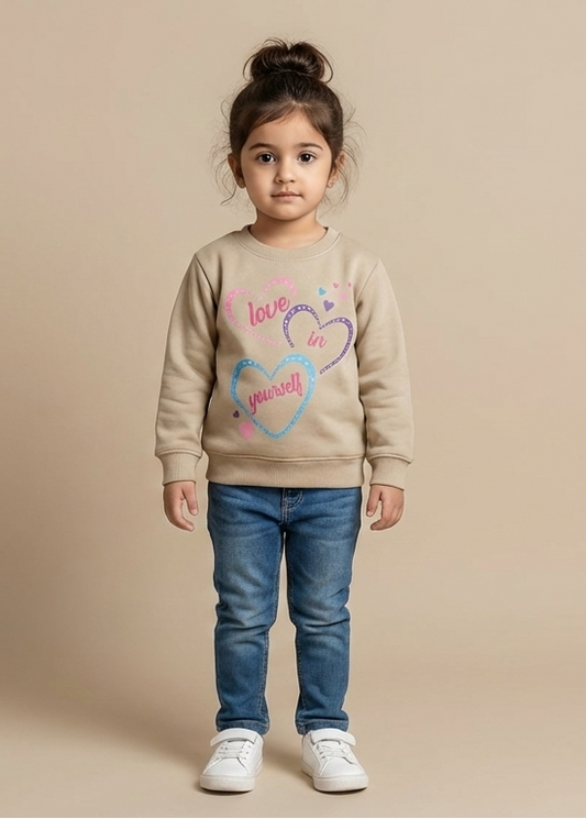 Child wearing a tan sweatshirt with a colourful heart design on a beige background