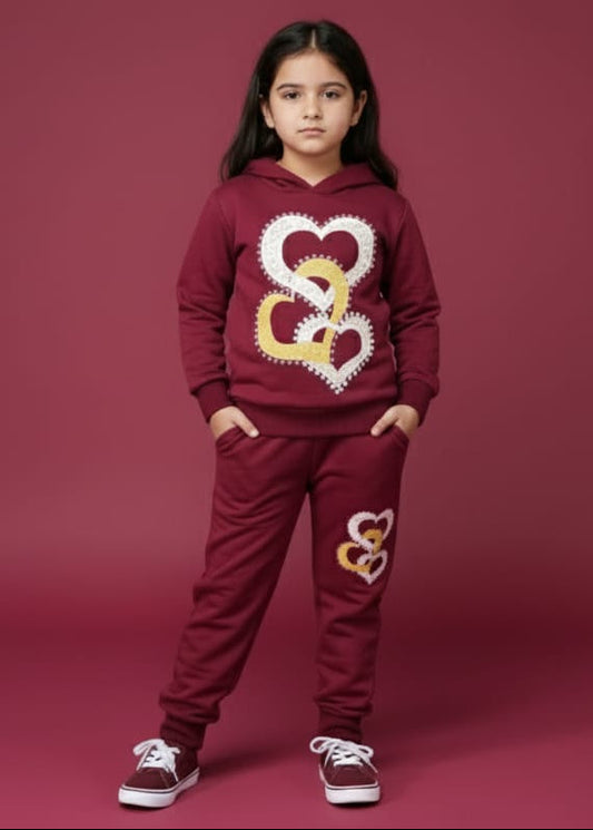 Girl wearing a maroon hoodie and pants with heart designs on a red background