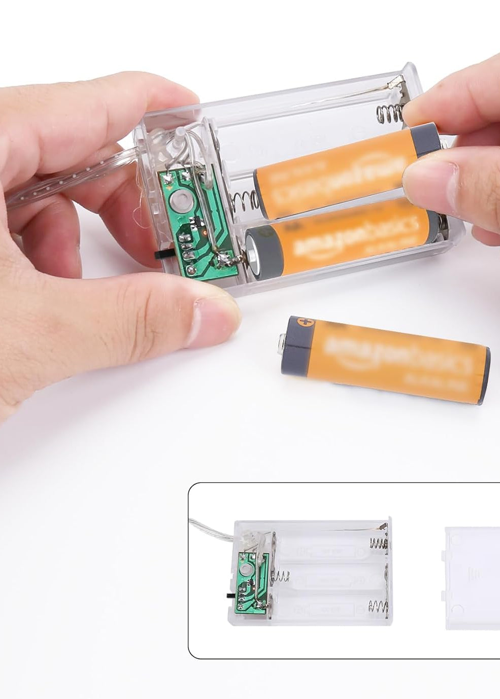 Hands holding a small electronic device with batteries and a white background