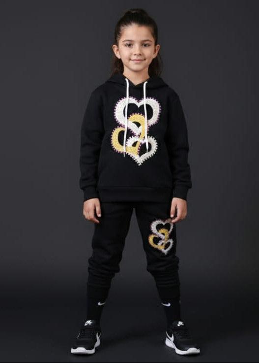 Person wearing a black hoodie and pants with logos on a dark background