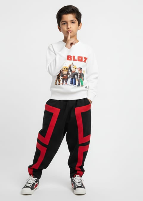 Person wearing a white sweatshirt with graphics and black pants with red accents on a white background
