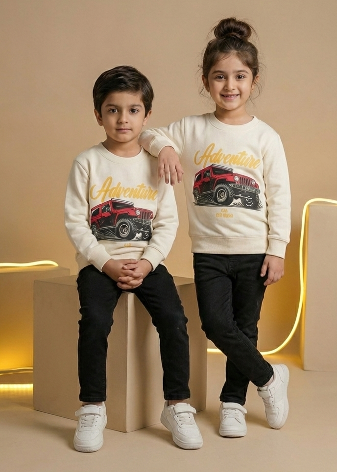 Two children wearing matching sweatshirts with car graphics on a beige background