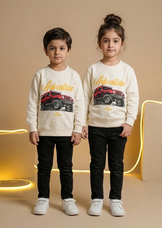 Two children wearing matching sweatshirts with car graphics on a beige background