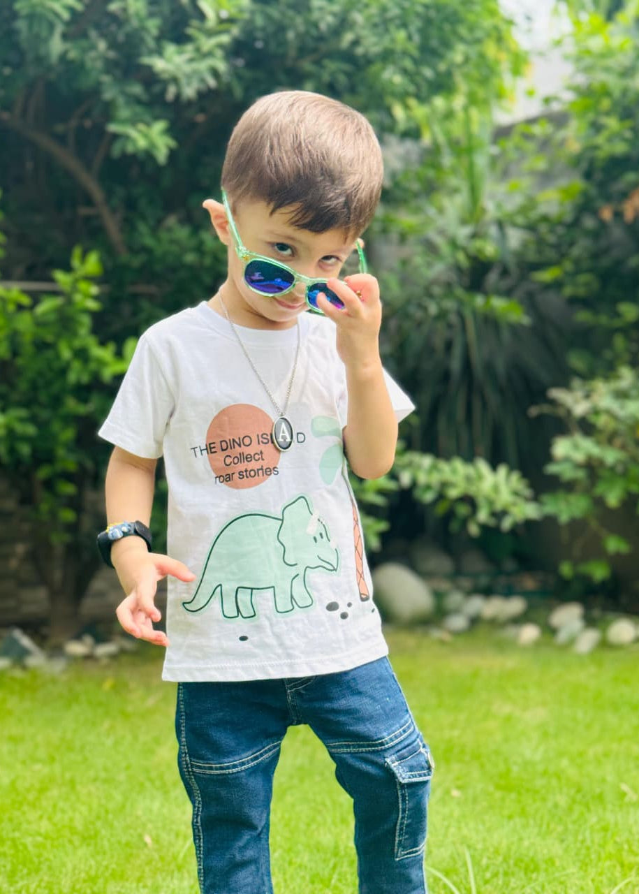 Child wearing sunglasses and a t-shirt with a dinosaur design outdoors