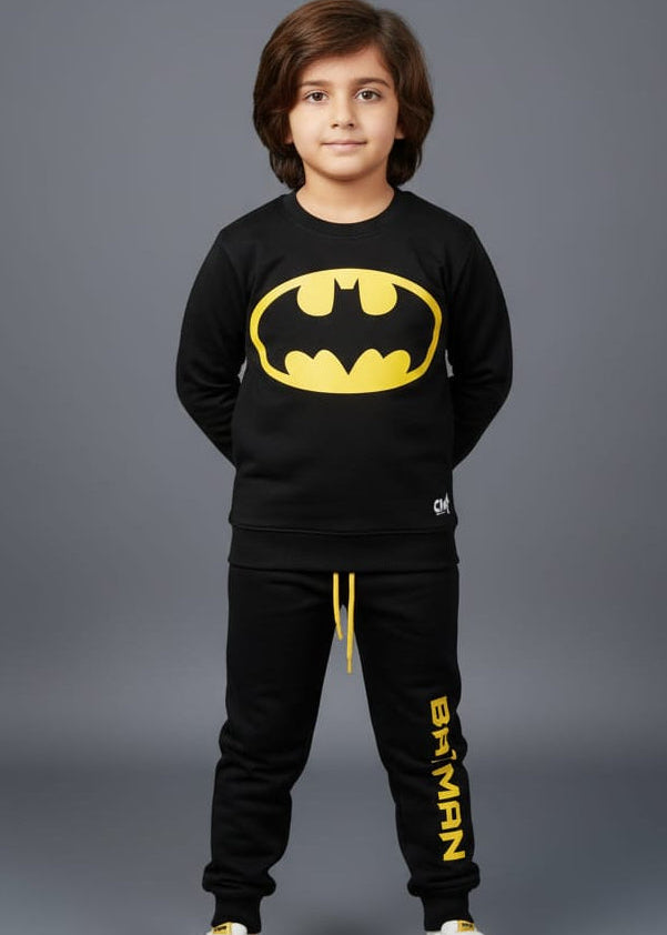 Child wearing a Batman-themed outfit with a black sweatshirt and pants on a gray background