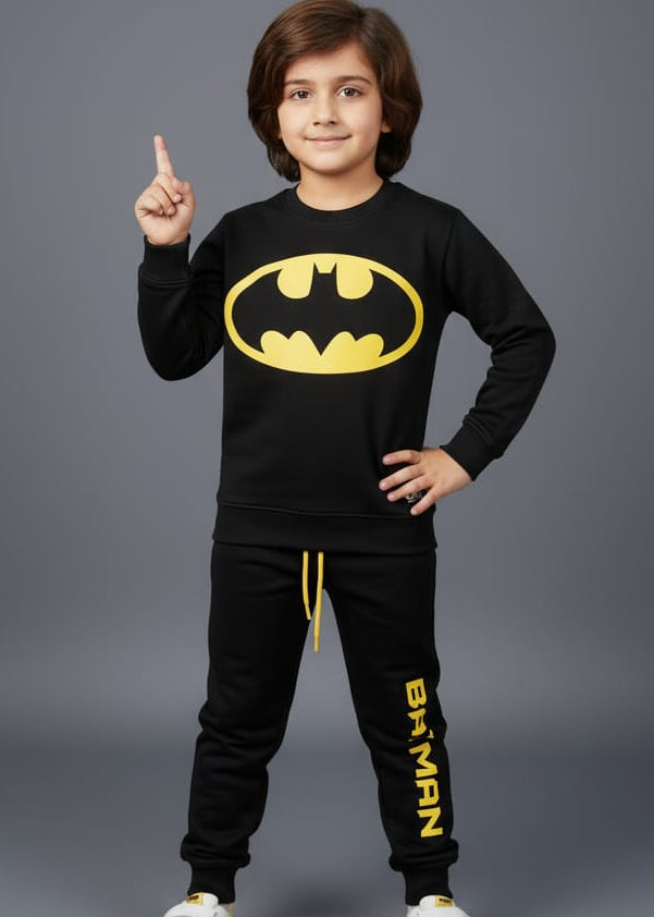 Child wearing a Batman-themed outfit with a black long-sleeve shirt and pants on a gray background