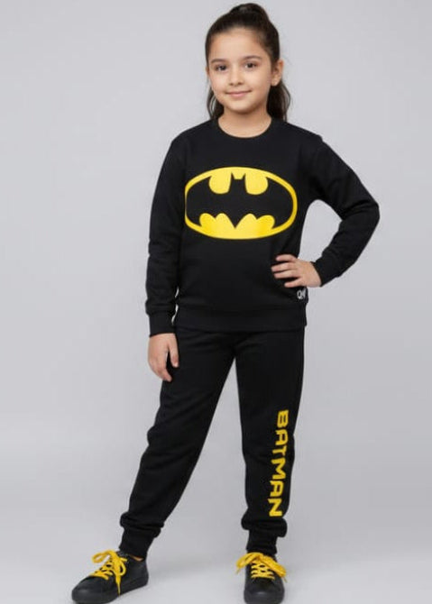 Child wearing a Batman-themed outfit with a black shirt and pants on a gray background