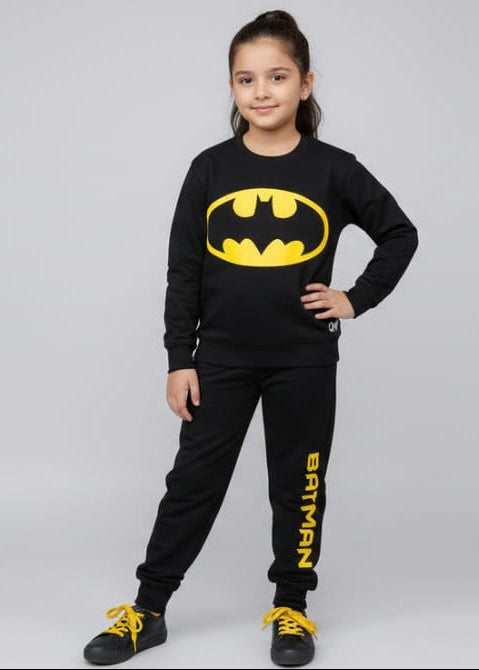 Child wearing a Batman-themed outfit with a black shirt and pants on a gray background