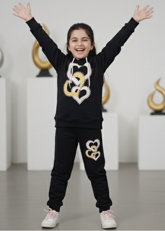 Person in black outfit with gold designs standing in a room with decorative elements.