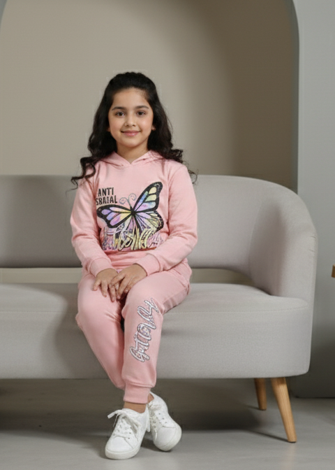 Young girl in pink outfit sitting on a gray sofa in a minimalistic room.