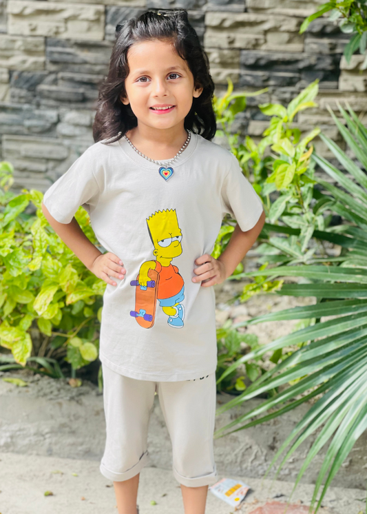 Child wearing a shirt with a cartoon character, standing outdoors with greenery and stone wall in the background