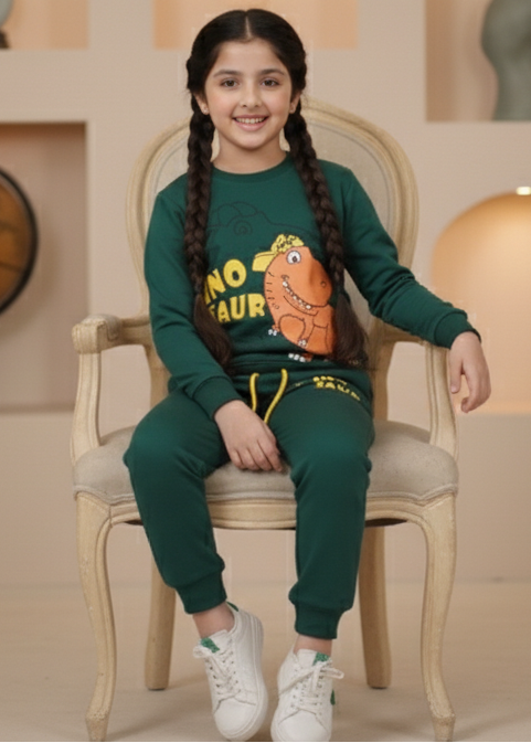 Young girl in a green dinosaur-themed outfit sitting on a chair.