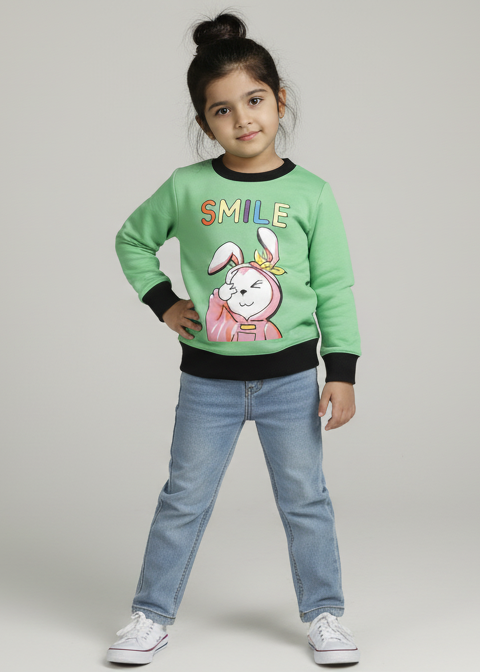 Child wearing a green sweater with a cartoon character and blue jeans on a gray background