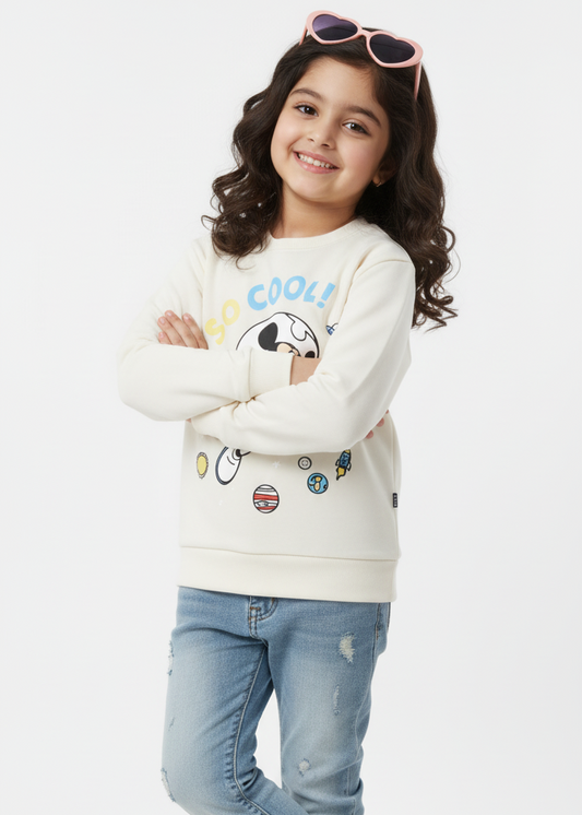 Young girl wearing a white sweatshirt with cartoon characters and blue jeans on a white background