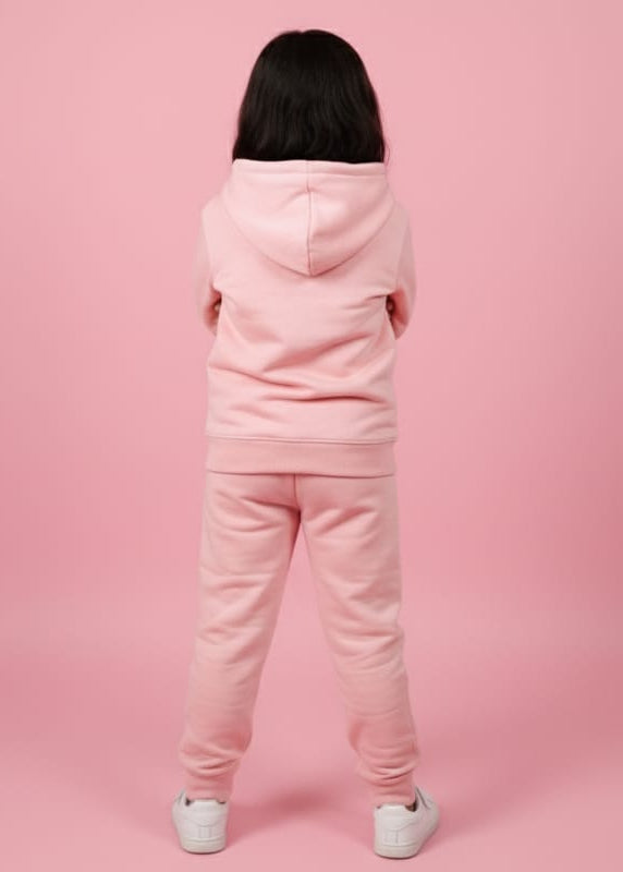 Person wearing a pink tracksuit against a pink background