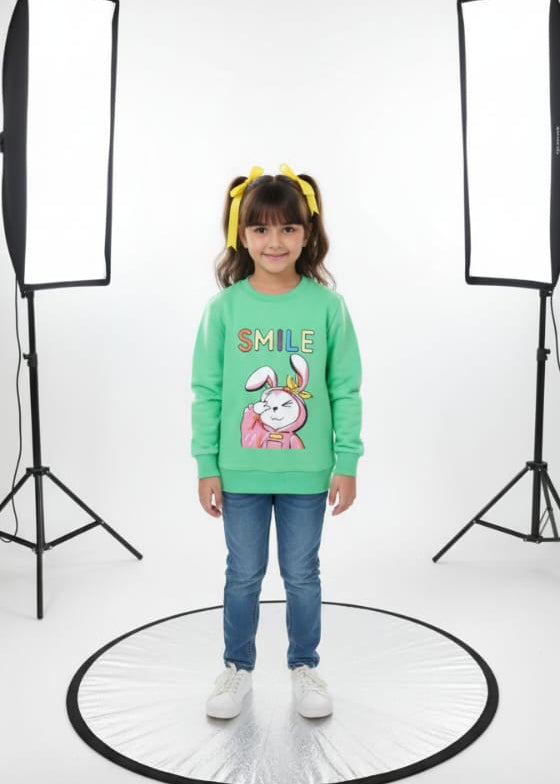 Child wearing a green sweater with a cartoon design on a white background