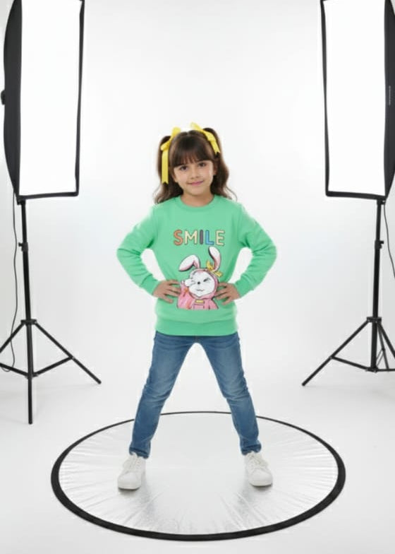 Child wearing a green shirt with cartoon characters in a photo studio setting