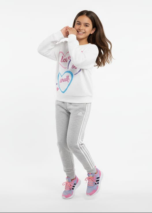 A Girl wearing a white sweatshirt with text and graphics, gray pants, and pink shoes on a white background